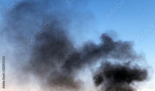 black smoke pillar against the blue sky background. © Dancing Man