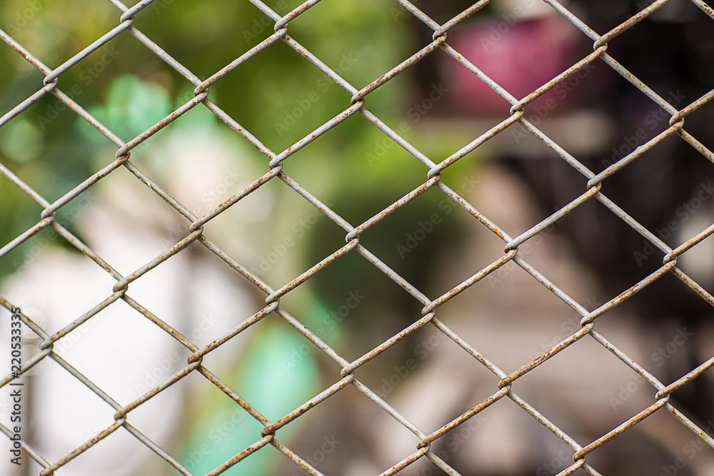Close up Chain Fence. Metal mesh . White tone. Dirty fence with blurred background. Metal net with green blued background,Steel Fence. 