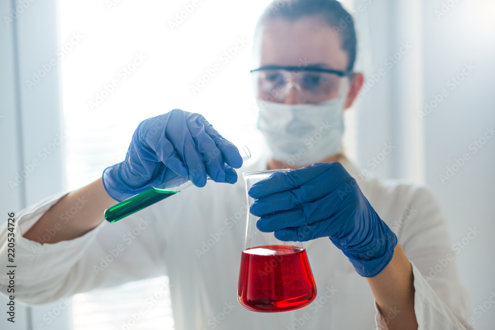 Scientist pouring chemical solution in erlenmeyer flask