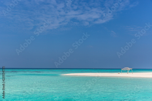 Amazing blue water in a desert island, blue sky day, wood hut © LMspencer