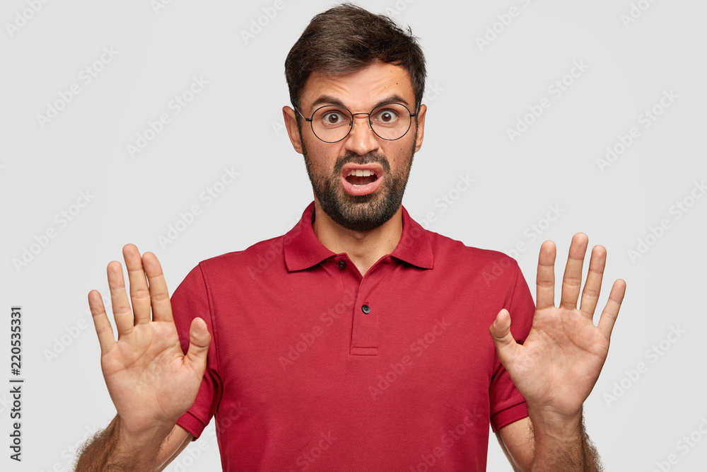 Naklejka premium Give me break, please! Annoyed bothered boss pulls palms towards camera, shows no gesture, refuses participate in business meeting, dressed in red casual t shirt, isolated on white studio wall