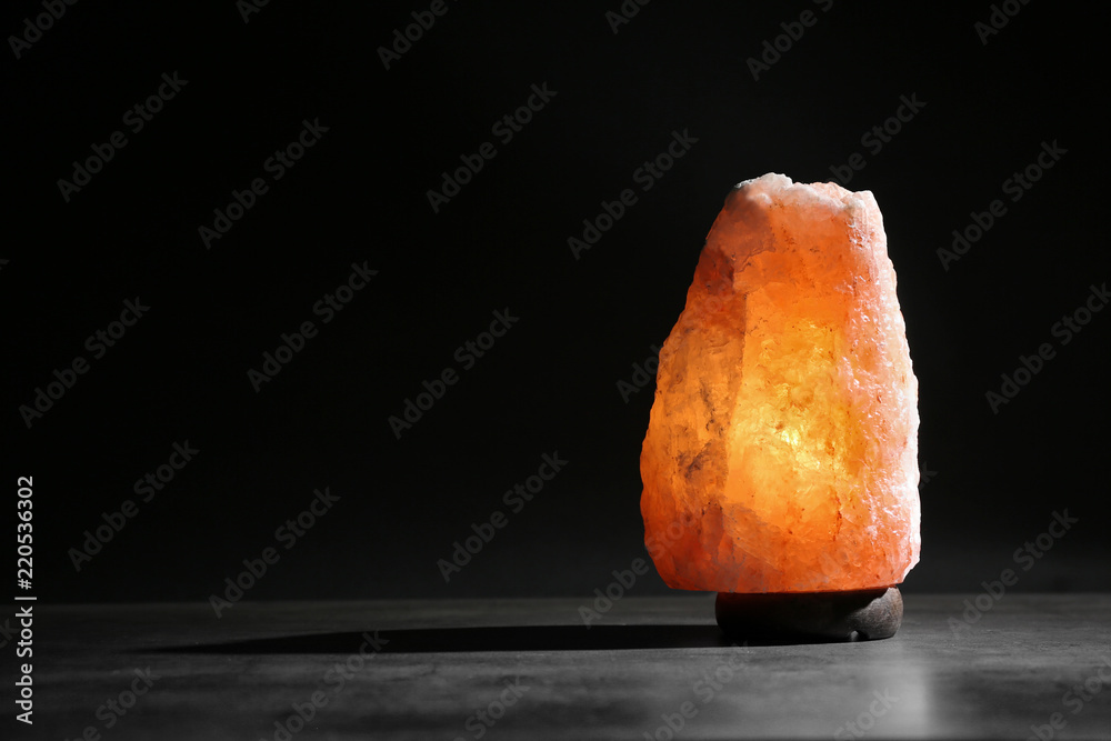 Himalayan salt lamp on table against black background. Space for text Stock  Photo | Adobe Stock