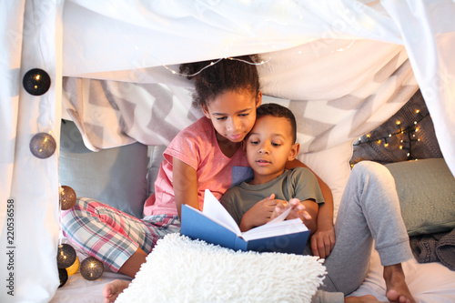 Foto African American children reading bedtime story at home