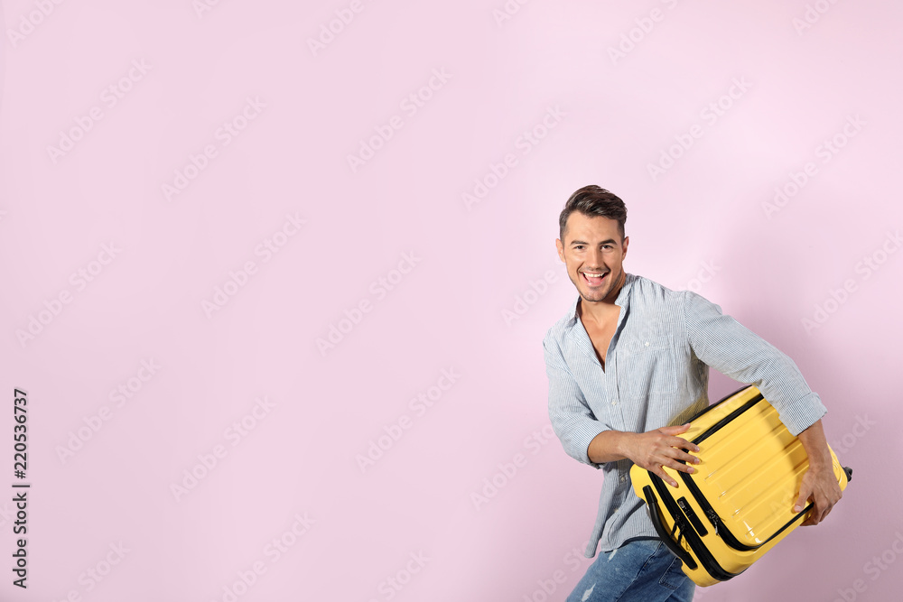 Young man with suitcase on color background. Space for text Young man with suitcase on color background. Space for text