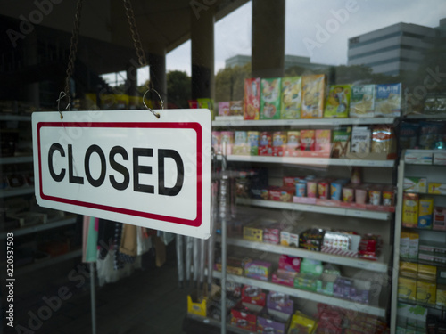 Close-up shot of a closed signage hanging on a glass door of a convenience store