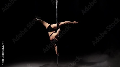 Girl dancing on a pole . Black smoke background. Slow motion