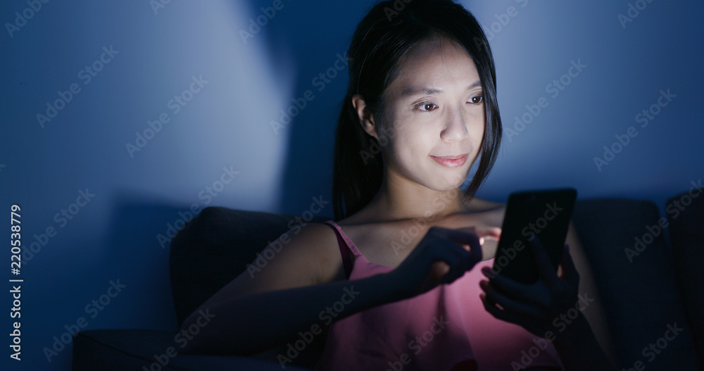 Woman use of mobile phone on sofa at night Woman use of mobile phone on sofa at night