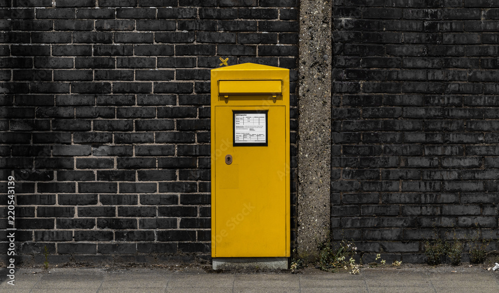 Gelber Postkasten vor einer Mauer Gelber Postkasten vor einer Mauer