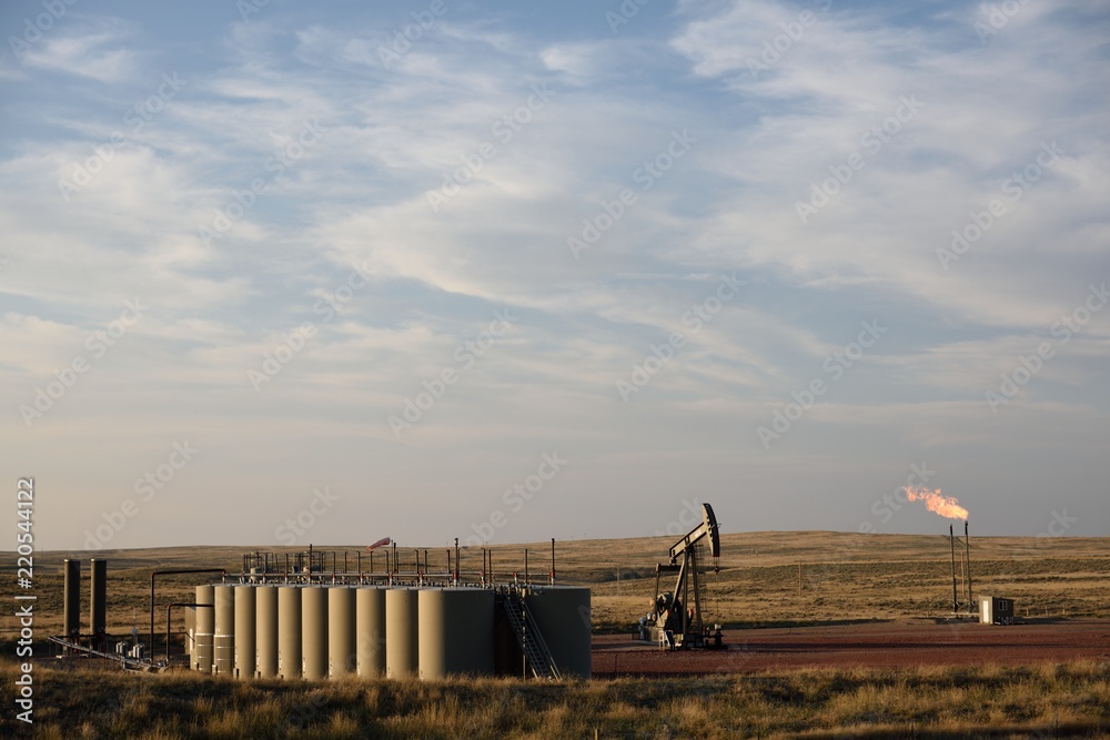 Wide distant view of a completed crude oil well site with a pump jack