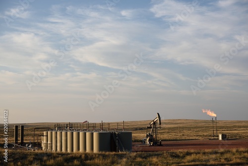 Wall Mural Wide distant view of a completed crude oil well site with a pump jack, natural g