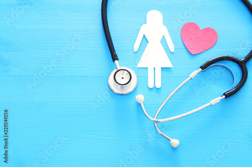 women healf Insurance . concept image of Stethoscope and female figure on wooden table. top view.