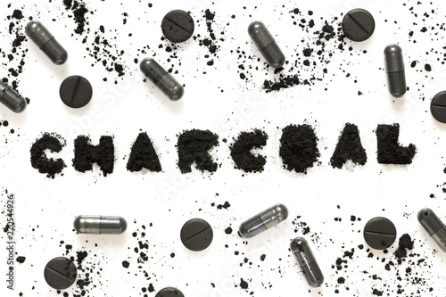 Activated charcoal powder and capsules (pills) isolated on white background, abstract pattern