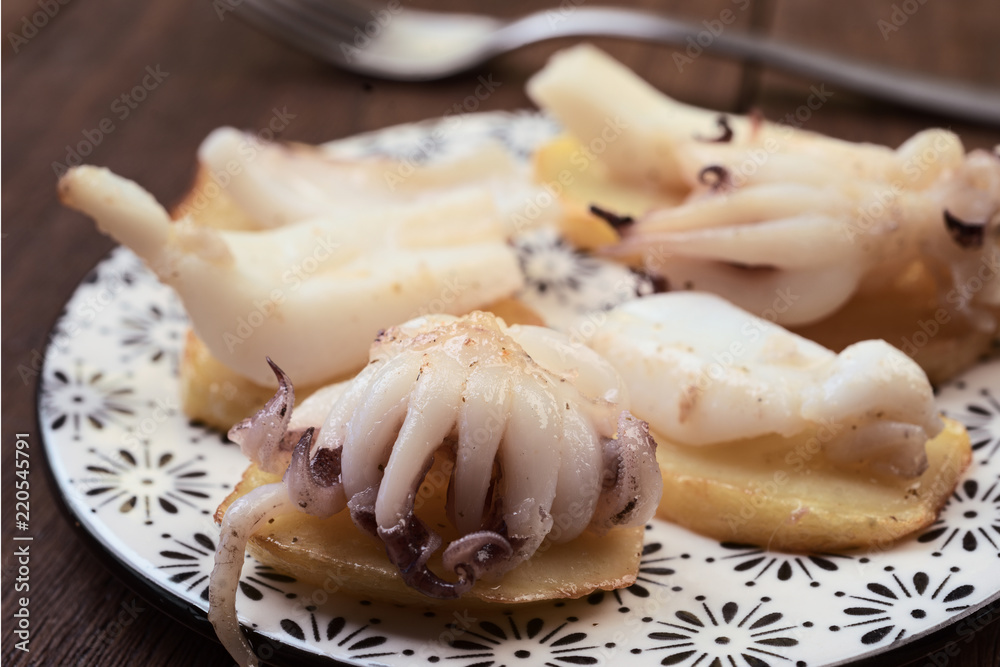 cuttlefish chopped on potatoes, on dark wooden board cuttlefish chopped on potatoes, on dark wooden board