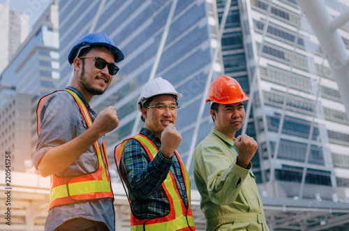 yeah, finally we did it, group of engineer, technician and architect screaming showing their strong hands together standing in modern city building background, construction site and industry concept