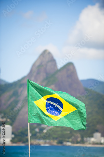 Brazilian flag flying in front of a bright view of Ipanema Beach with Two Brothers Mountain in Rio de Janeiro, Brazil photo