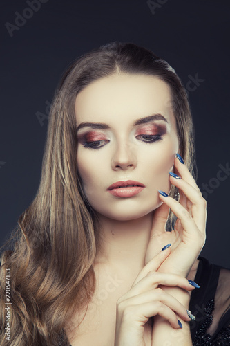 Glamour girl portrait with bright smokey eyes make-up  hands near face  hair style. Dark background. Studio portrait