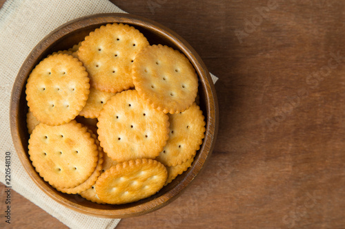 Round salted cracker cookies in wooden bowl putting on linen and wooden background. photo