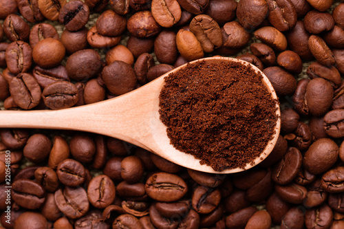 Ground coffee in a spoon on the background of whole coffee beans