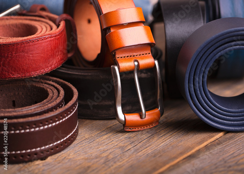 Collection of leather belts on a wooden table photo