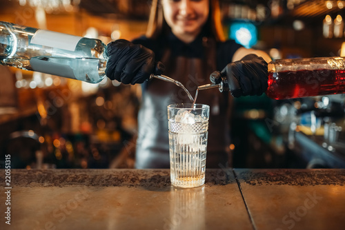 Woman bartender mixing alcoholic coctail in pub photo