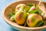 Juicy pears on the wooden bowl and blue table