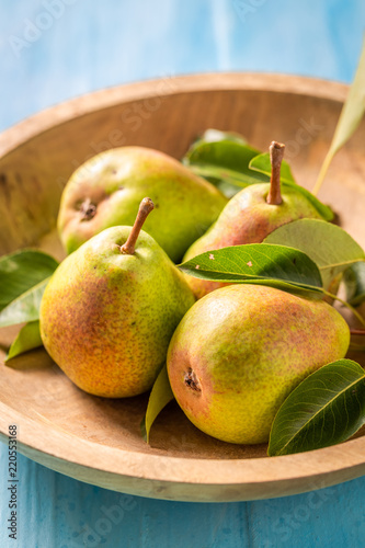 Healthy pears on the wooden bowl and blue table