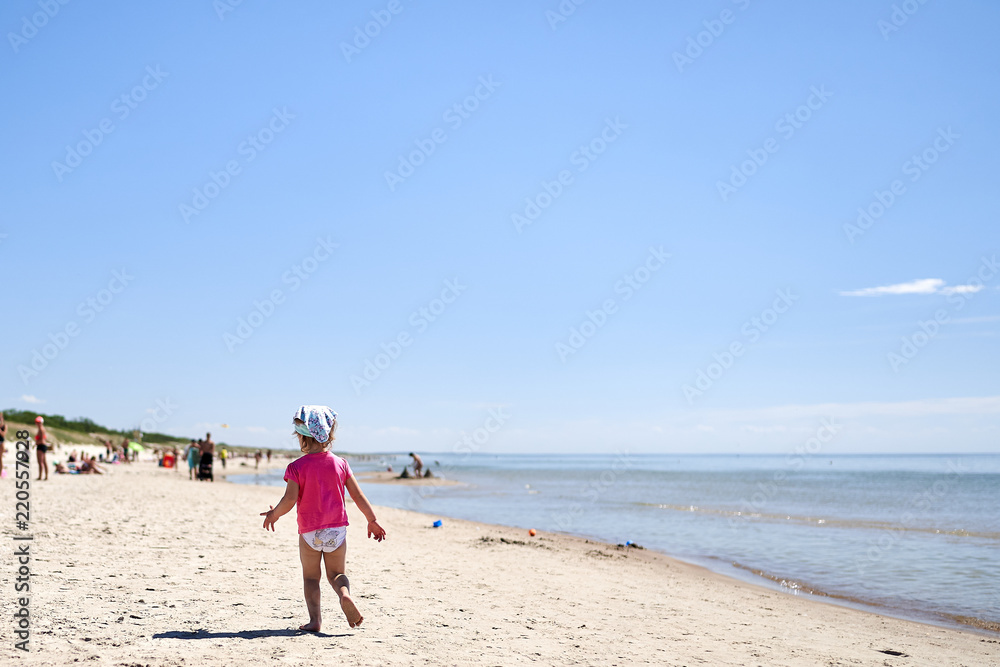 girl child is playing in the sandy beach in summer