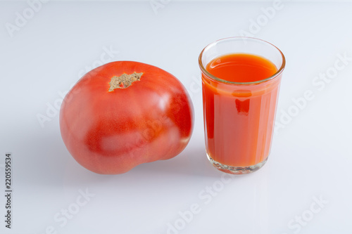 Large tomato and a glass of tomato juice photo