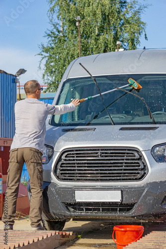 The driver is washing his minibus