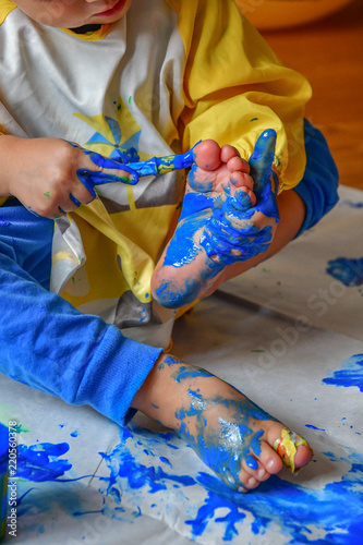 Kleinkind beim Malen mit Fingerfarben malt sich F    e an
