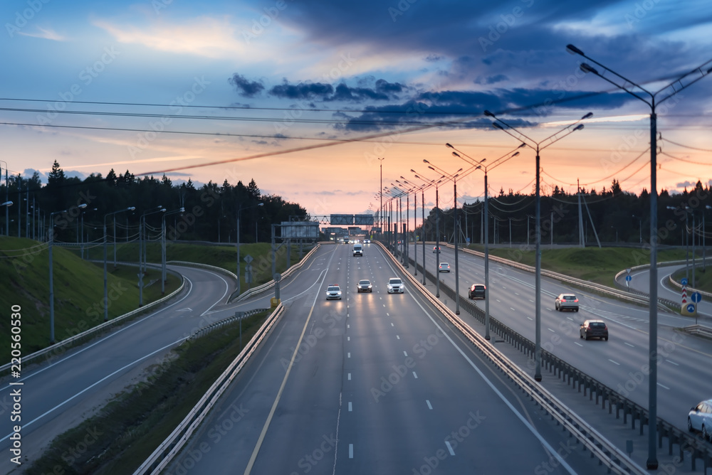 Fototapeta premium Car and light on the road. Sunset on the evening highway with metal safety barrier