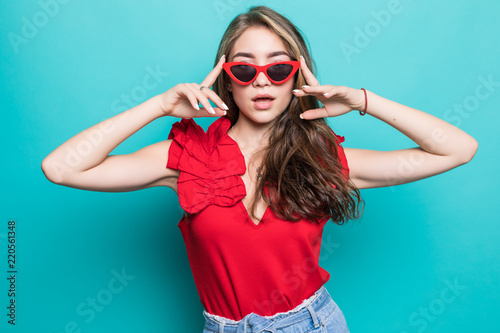 Young woman in sunglasses in summer dress isolated on blue background