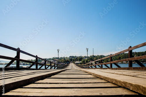 Perspective line from the lower view of long wood bridge. wide image for background, wallpaper, copy space, article and postcard. image for promote tourism. Mon Bridge, Sangkhla Buri, Kanchanaburi. © kanpisut