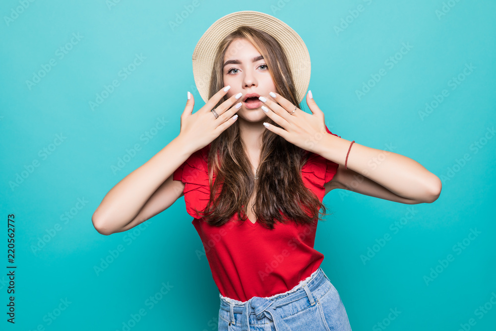 Close up portrait of a happy excited young woman in beach hat with mouth open looking at camera over blue background Close up portrait of a happy excited young woman in beach hat with mouth open looking at camera over blue background