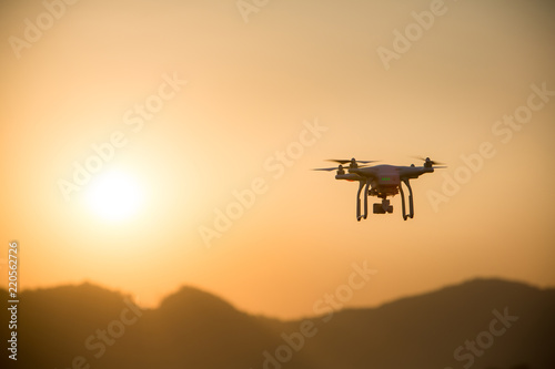 drone copter flying with digital camera.Drone with high resolution digital camera. Flying camera take a photo and video.The drone with professional camera takes pictures of the misty mountains. © kanpisut