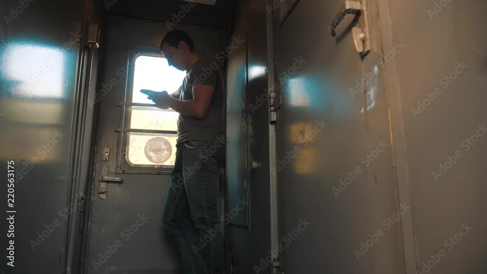 the man silhouette is standing on the train Railway carriage holding a smartphone and . slow motion video. man writes messages in the smartphone in the train social lifestyle media. man with