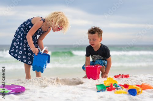 Girl and boy playing with sand castle on beach