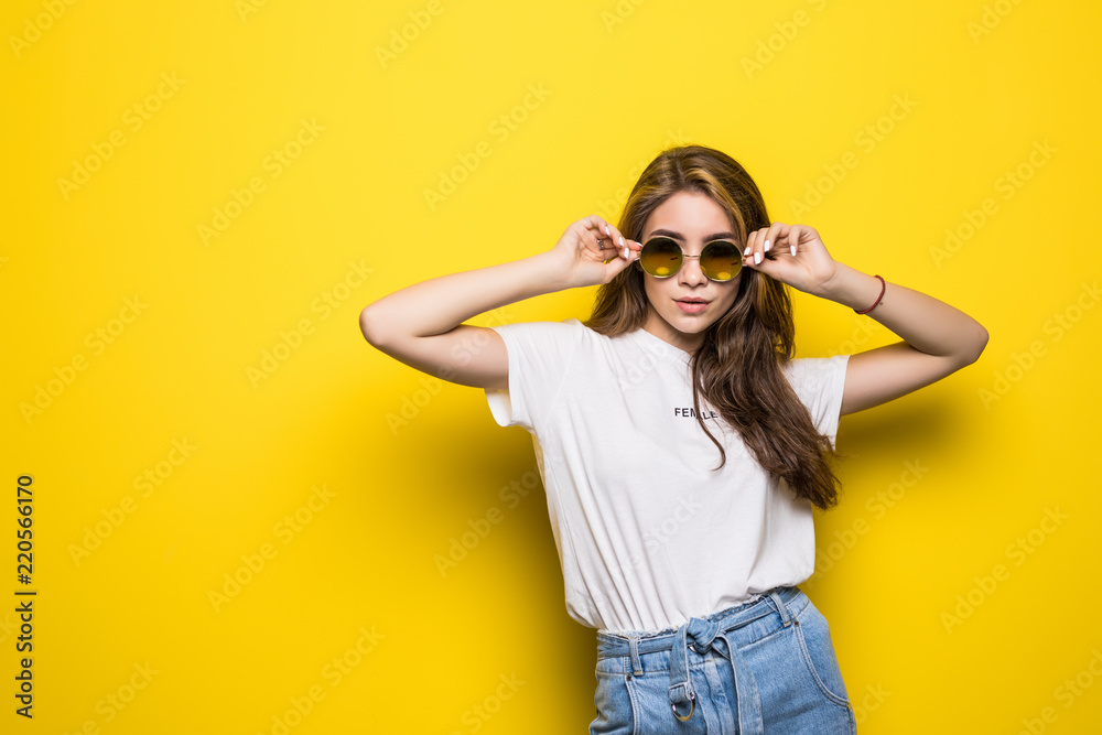 Young trendy woman with sunglasses on a yellow background Young trendy woman with sunglasses on a yellow background