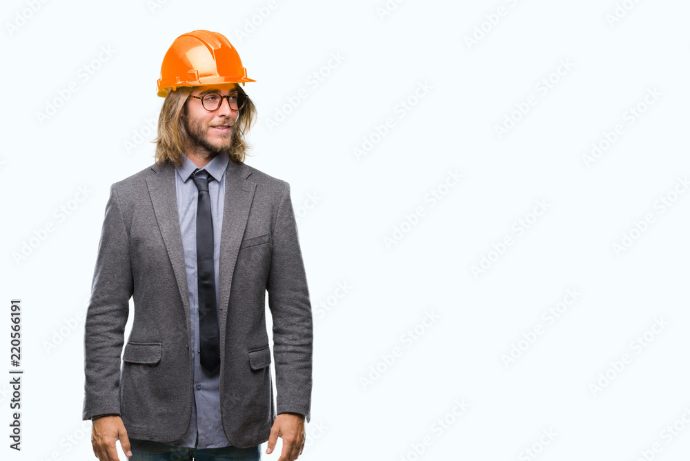 Young handsome architec man with long hair wearing safety helmet over isolated background smiling looking side and staring away thinking. Young handsome architec man with long hair wearing safety helmet over isolated background smiling looking side and staring away thinking.
