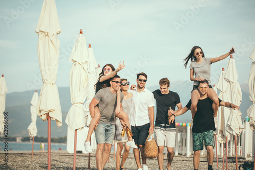 Friends on beach walking, having fun, dancing, couples hugging