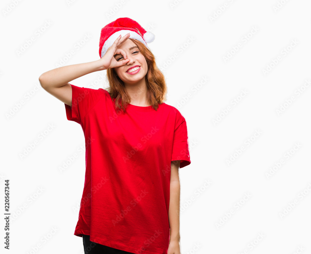 Young beautiful woman over isolated background wearing christmas hat doing ok gesture with hand smiling, eye looking through fingers with happy face. Young beautiful woman over isolated background wearing christmas hat doing ok gesture with hand smiling, eye looking through fingers with happy face.