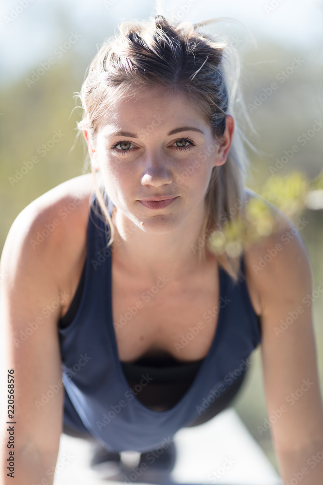 Young female athlete doing push-up in blue top Young female athlete doing push-up in blue top