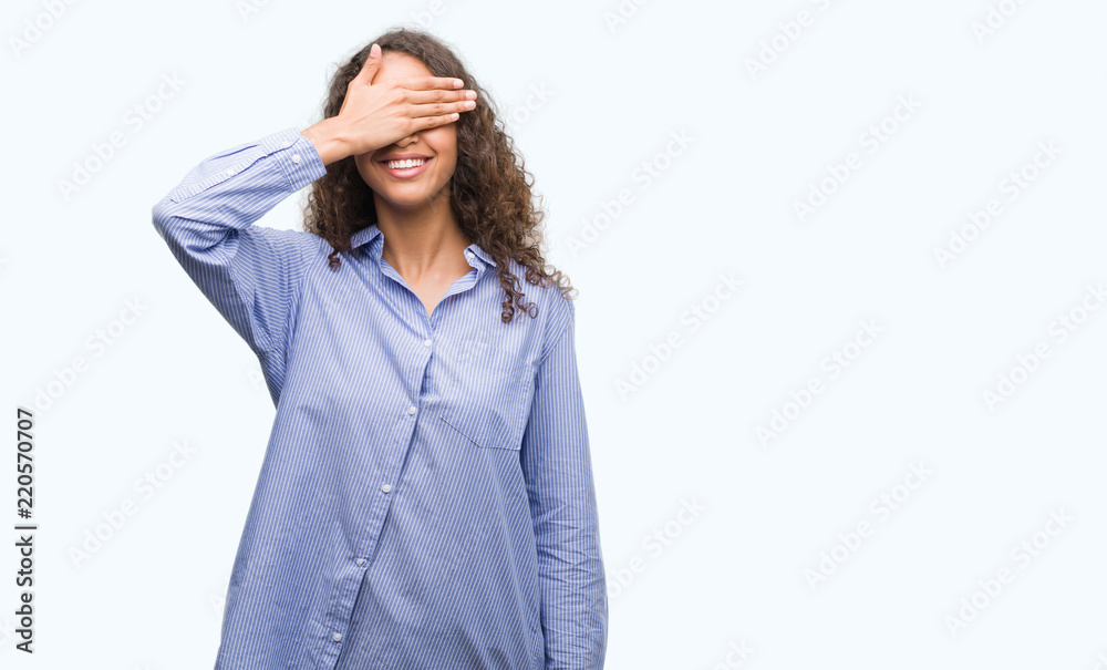 Young hispanic business woman smiling and laughing with hand on face covering eyes for surprise. Blind concept.