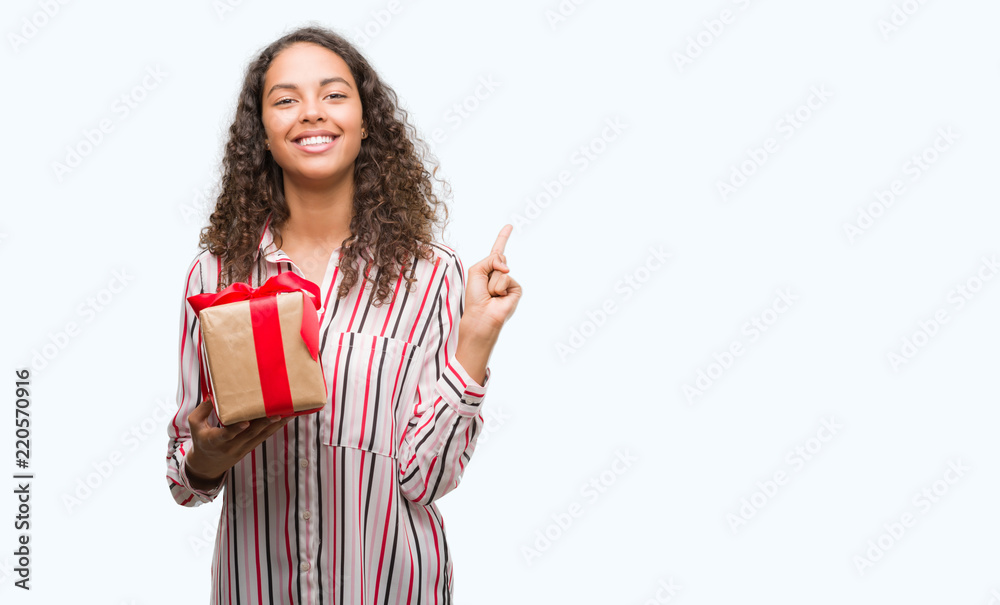 Young hispanic woman in love holding present very happy pointing with hand and finger to the side Young hispanic woman in love holding present very happy pointing with hand and finger to the side