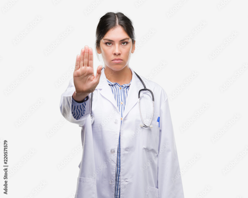 Young hispanic doctor woman with open hand doing stop sign with serious and confident expression, defense gesture Young hispanic doctor woman with open hand doing stop sign with serious and confident expression, defense gesture