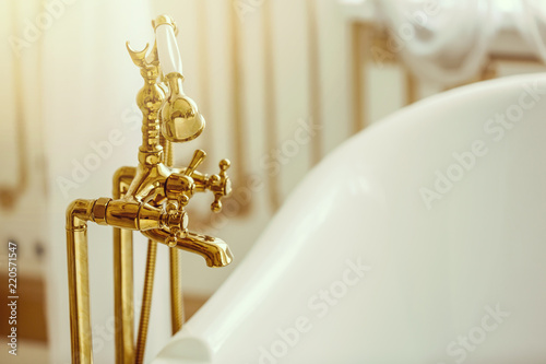 Rich gold faucet and white bath in the bathroom