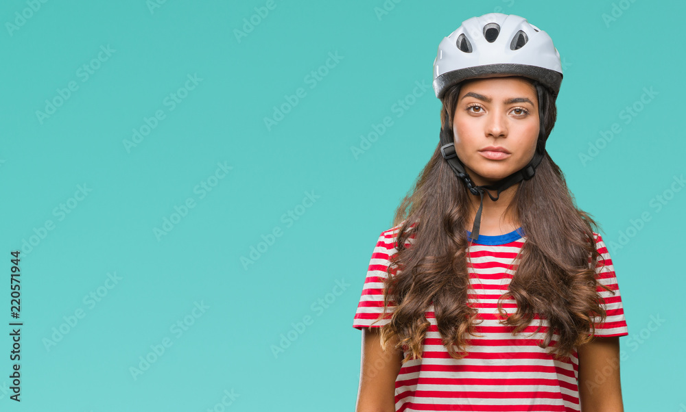 Young arab cyclist woman wearing safety helmet over isolated background with serious expression on face. Simple and natural looking at the camera. Young arab cyclist woman wearing safety helmet over isolated background with serious expression on face. Simple and natural looking at the camera.