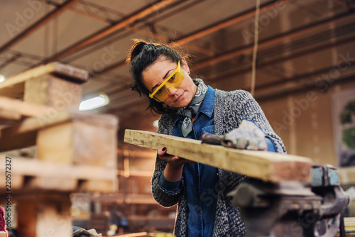 Picture of middle age focused female carpenter looking and choosing wood for her work in a workshop. photo