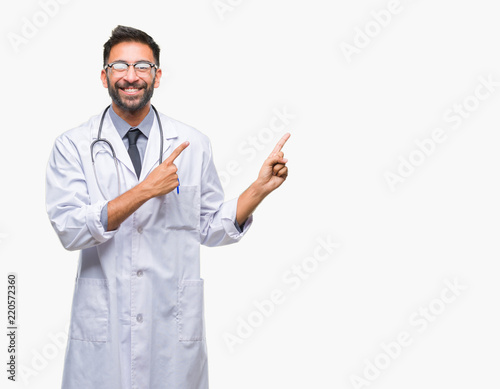 Adult hispanic doctor man over isolated background smiling and looking at the camera pointing with two hands and fingers to the side.