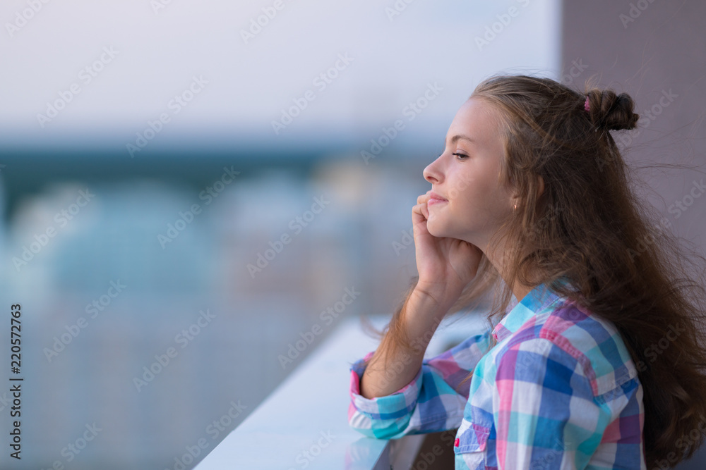 Young woman leaning on a parapet daydreaming
